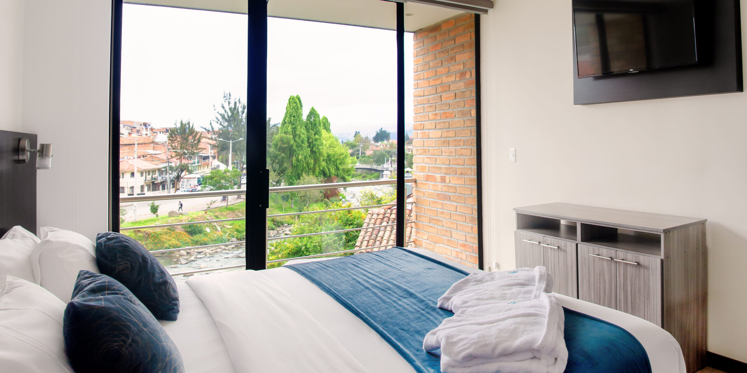 Cama doble con vista al río Tomebamba Suite de hotel con detalles en madera y cristal